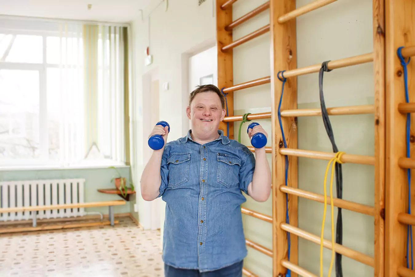 A disabled man smiling while holding with the dumbell